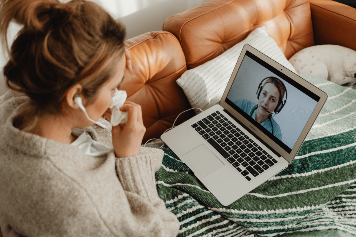 Person on a laptop video visit with a clinician from the couch